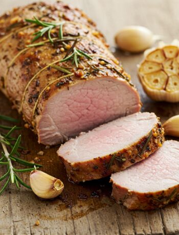 liced garlic-rosemary pork tenderloin on wooden board