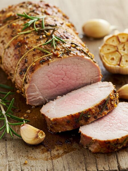 liced garlic-rosemary pork tenderloin on wooden board