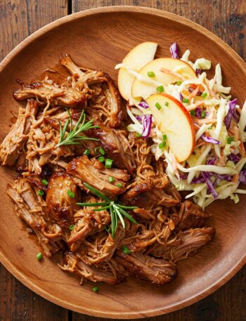 ender pulled pork served with fresh apple-cabbage slaw on a wooden plate